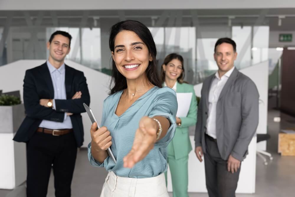 Emprendedora dando la bienvenida a nuevos colaboradores en una oficina de seguros.